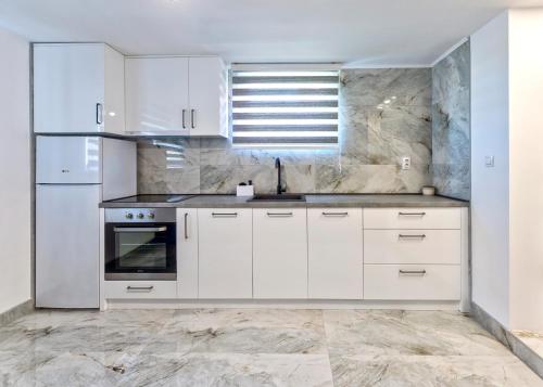a white kitchen with white cabinets and a sink at Evergreen Escape Apartment in Užice