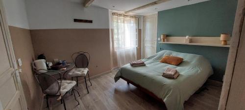 a bedroom with a bed and a table and chairs at La Fischaumière in Soleilhas