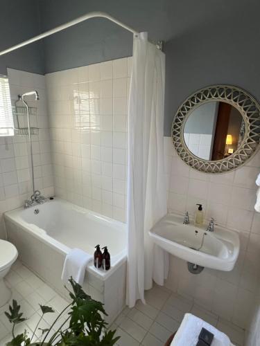a bathroom with a tub and a sink and a mirror at Kamieskroon Hotel in Kamieskroon