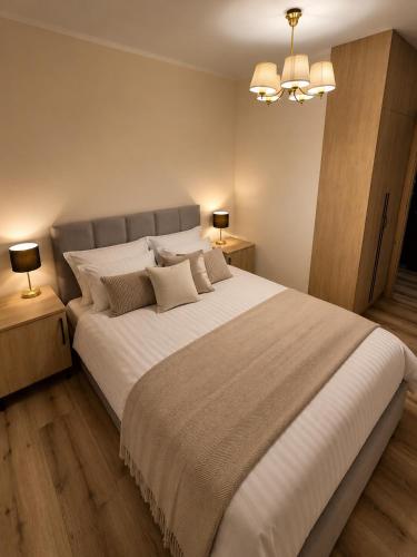 a bedroom with a large white bed with two lamps at Sportova Elegance Apartment in Płock