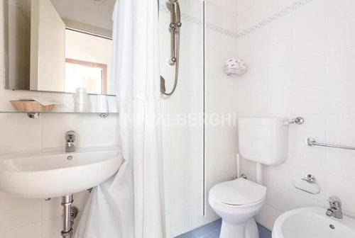a white bathroom with a toilet and a sink at Hotel New York in Cervia