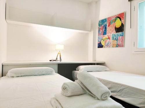 two beds in a room with a lamp on the wall at Chill and Beach in Torremolinos