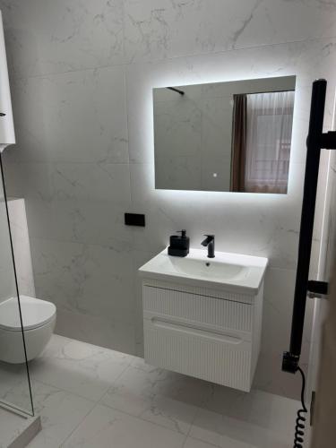 a white bathroom with a sink and a mirror at Поляна Апарт in Polyana