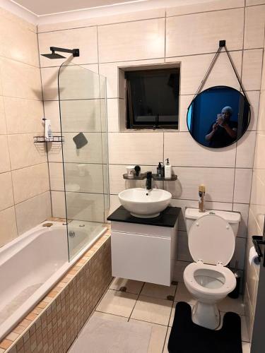 a bathroom with a toilet and a sink and a mirror at Kay's Guest House in Kraaifontein