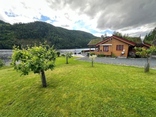 a house with trees in the grass next to a lake at Lakefront Cabin on Vråvatn in Kviteseid