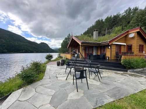 a log cabin with a table and chairs next to a lake at Lakefront Cabin on Vråvatn in Kviteseid