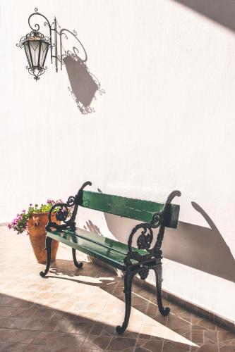 a green bench with a lamp and a potted plant at Iliada Beach Hotel in Gouvia