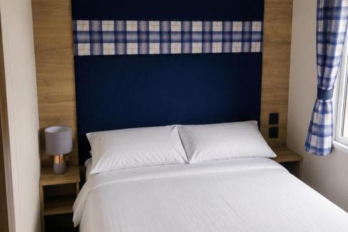 a bedroom with a white bed with a blue headboard at 3 Bed - Sleeps 8 - Family & Pet Friendly in Skegness
