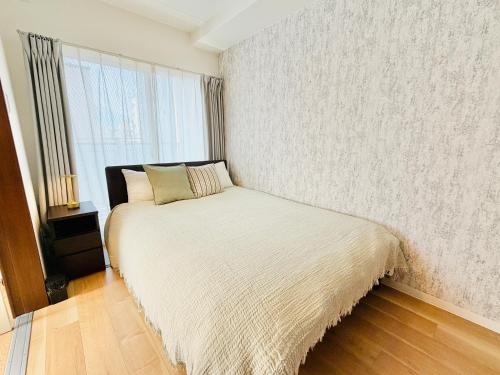a bedroom with a bed in a room with a window at u-heim Osaka Tengachaya in Osaka
