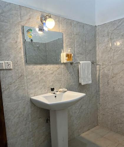 a bathroom with a white sink and a mirror at Pearl Resort in Arugam Bay