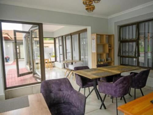 a dining room with a wooden table and purple chairs at 5@Partridge Guesthouse in Newcastle