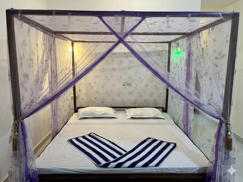 a canopy bed with blue and white striped pillows on it at Pearl Resort in Arugam Bay