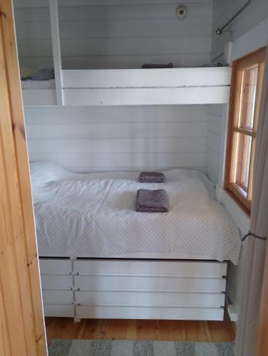 a small bed in a small room with a window at Lomamökki Rantaniemi in Töfsala