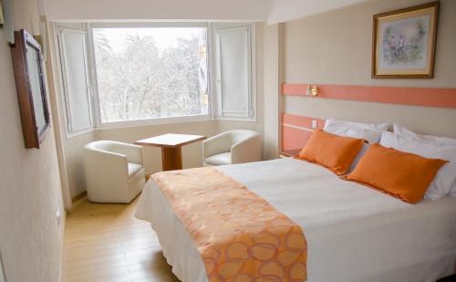 a bedroom with a bed with orange pillows and a window at Hotel Dior in Tandil