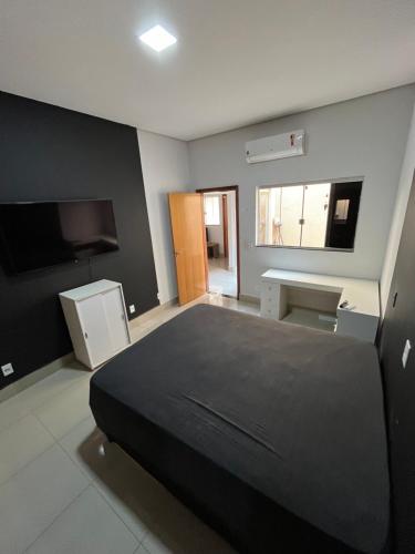 a bedroom with a black bed and a television at CASA para TEMPORADA in Barra do Garças