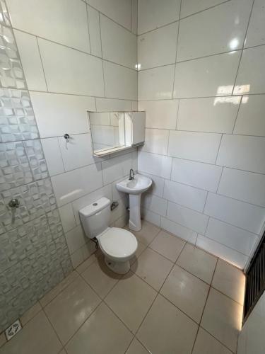 a white bathroom with a toilet and a sink at CASA para TEMPORADA in Barra do Garças