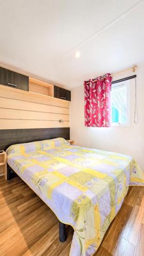 a bedroom with a large bed with a colorful comforter at Le Cottage D'Oléron, Mer et Animation Camping in Saint-Pierre-dʼOléron