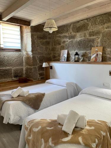 a bedroom with three beds and a stone wall at As Fontaiñas in Beiro