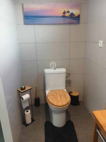 a bathroom with a toilet with a wooden seat at Chez Sab et chaton in Saint-Leu
