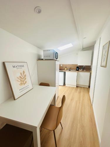 a white table and chairs in a room with a kitchen at Aytré plage in Aytré