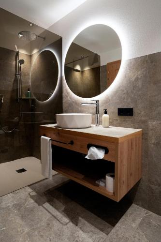 a bathroom with a sink and two mirrors at Hotel Ciamp in Santa Cristina Gherdëina