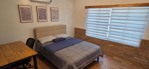 a bedroom with a bed and a table and a window at Modern Industrial Artsy Apt Remodel Secure in Matamoros