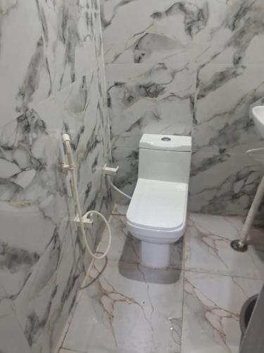a bathroom with a white toilet in a stone wall at HOTEL KRISHNAM Inn in Mathura