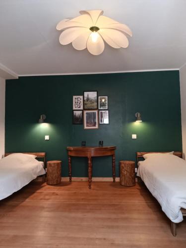 a room with two beds and a table and a green wall at Nids des cigognes in Furchhausen