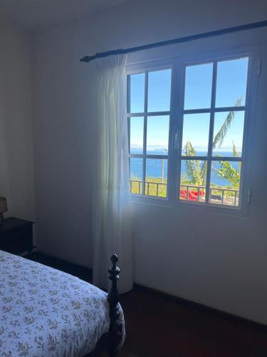 a bedroom with a bed and a large window at Casa 52 in Machico