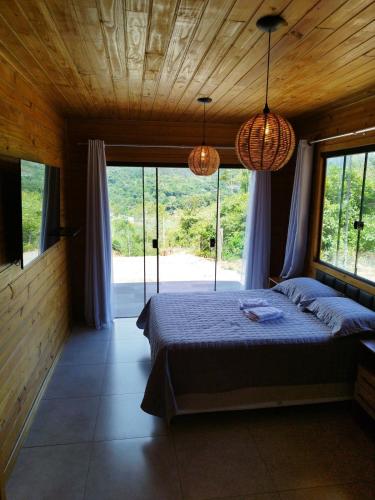 a bedroom with a bed and a large window at Cabana Mais Natureza in Santo Amaro da Imperatriz