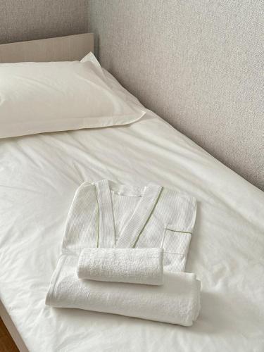 a white bed with two towels on it at Moskovskaya in Atyrau
