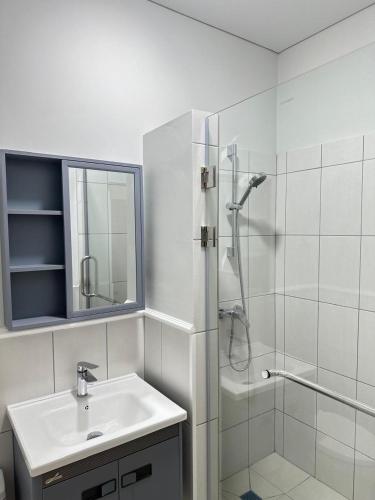 a white bathroom with a sink and a shower at Moskovskaya in Atyrau
