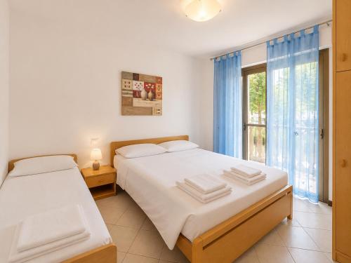 a bedroom with two beds and a window at Anthea - Timavo apartament 1 in Lignano Sabbiadoro