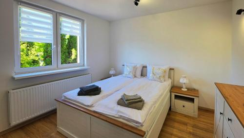 a bedroom with a large white bed and two windows at Agroturystyka w Folwarku Uradz in Tarmno