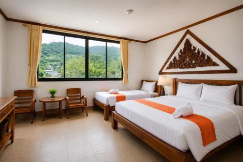 a hotel room with two beds and a desk at Onnicha Hotel Phuket in Phuket