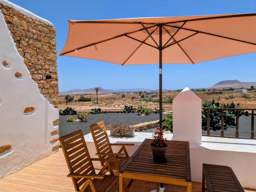 a patio with a table and an umbrella at Los Nopales Fuerteventura in Antigua