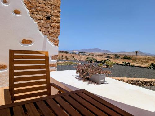 a wooden bench sitting on a porch with a view of the desert at Los Nopales Fuerteventura in Antigua