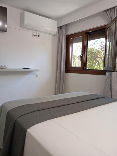 a white bedroom with a bed and a window at Calma Kourouta Apartments in Kourouta