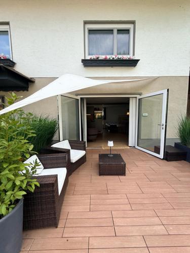 a patio with a white umbrella and chairs and a table at FACT Apartments in Arnoldstein