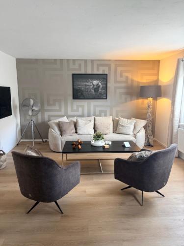 a living room with a couch and two chairs at FACT Apartments in Arnoldstein
