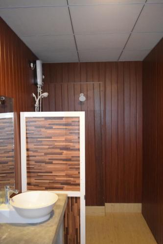 a bathroom with a white sink and a wooden wall at Elephant Arcade Yala in Tissamaharama