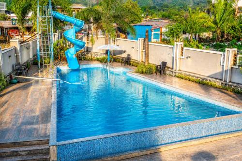 a blue water slide in the middle of a pool at Royal Heritage Lonavla - 7BHK with Turf in Lonavala