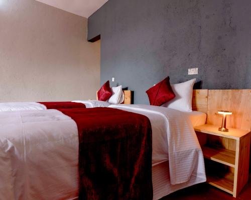 a bedroom with two beds with white and red pillows at Marera Eco Lodge in Karatu