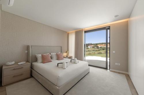 a bedroom with a large white bed and a large window at Quinta da Lagoeira in Caldas da Rainha