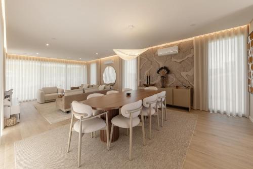 a dining room with a wooden table and white chairs at Quinta da Lagoeira in Caldas da Rainha