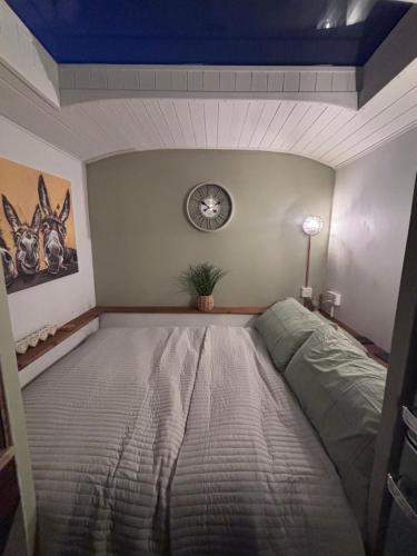 a bedroom with a bed and a clock on the wall at The Carriage Lorry at Tilleys Glamping in Birchington