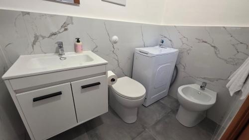 a white bathroom with a toilet and a sink at Mari del sud in Bagheria