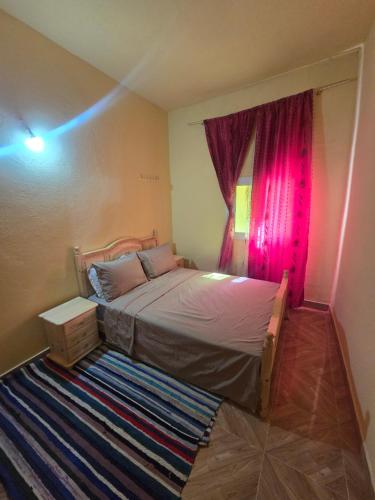 a bedroom with a bed and a window with pink curtains at Gîte Dayet Chiker in Taza