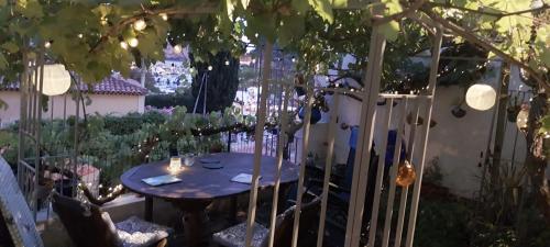 a table and chairs in a garden with a tree at Votre terrasse vue mer sous la vigne, un havre de paix in Ensuès-la-Redonne