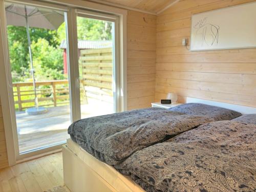 a bedroom with a bed and a large window at Älg Stuga in Kosta